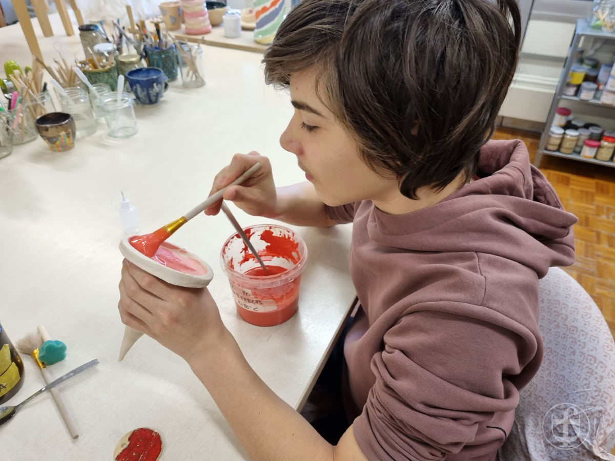 Raphael bemalt das Dach mit roter Farbe. Fotografie von Daniela Joss