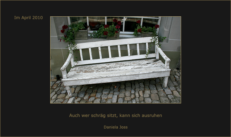 Alte weisse Bank mit roten Geranien.