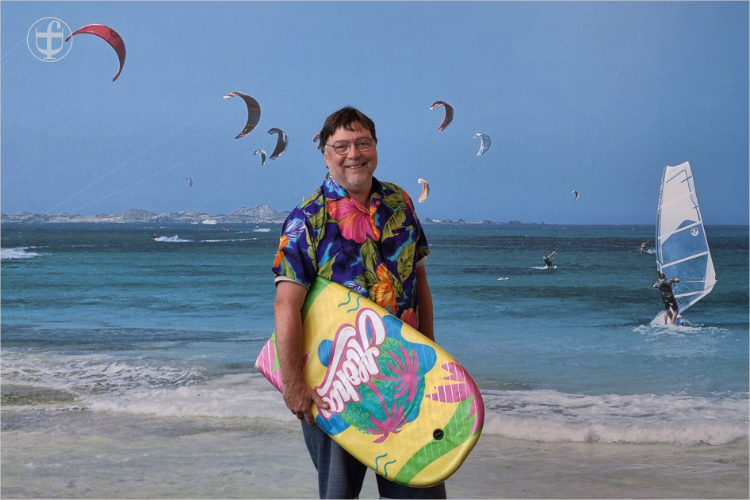 Fred mit einem Hawaii-Hemd und einem Surfbrett unter dem Arm am Strand von Daniela Joss
